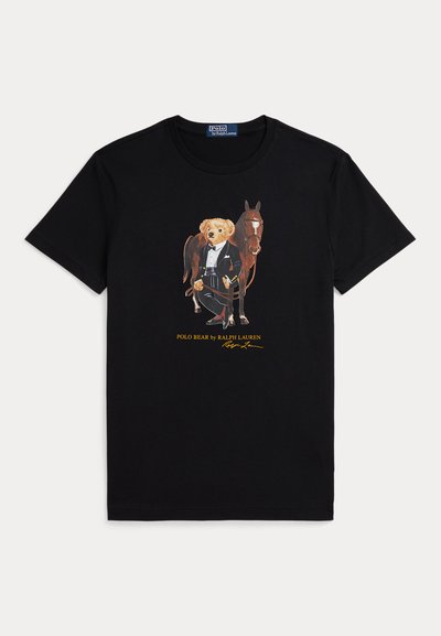 Svart t-shirt med grafik av en nallebjörn klädd i formell ridsportutrustning som står bredvid en brun häst.