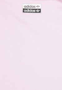 Logo Adidas na černobílém pozadí na světle růžové fabrice.