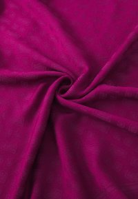 Fuksija tkanina glatke teksture, s suptilnim geometrijskim uzorkom. Materijal ima blagi sjaj, savijen u spiralu.