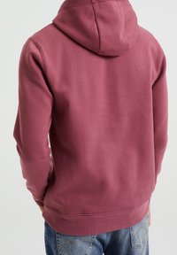 Burgundy hoodie med en känguruficka och justerbar drarem. Mjuk bomullsblandning, ribbade ärmslut och nederkant.