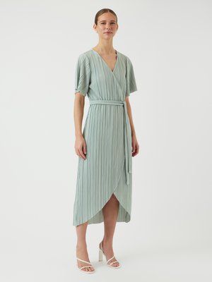 Pleated wrap dress in light teal, featuring short flutter sleeves, a belted waist, and an asymmetrical hem. Smooth fabric texture.