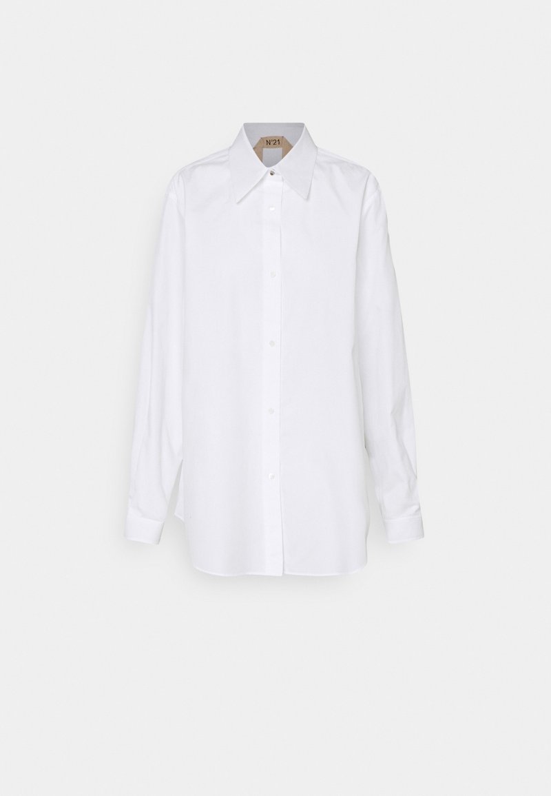 Camicia bianca con colletto ampio, maniche lunghe e taglio dritto. Realizzata in un tessuto leggero e liscio. Dettagli minimal.