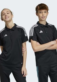 Zwarte sportieve polo shirts met witte drie-streep accenten op de schouders, voorzien van een kraag en knoopsluiting, gecombineerd met bijpassende broeken.