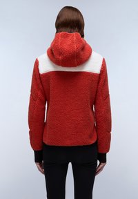 Red fleece jacket featuring a white shoulder panel, a hood, textured fabric, and black cuffs, designed for warmth and comfort.