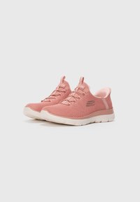 Pair of pink Skechers fabric sneakers with white soles, elastic laces, and pull tabs on a plain light background.