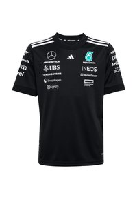 Černý sportovní dres s kulatým výstřihem, krátkými rukávy a bílými akcenty. Na přední straně jsou výrazně zobrazeny různé loga sponzorů.