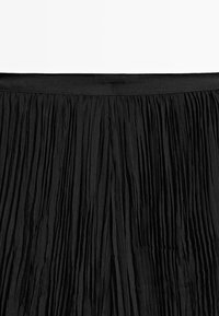 Black pleated skirt with a textured fabric and a smooth waistband, featuring multiple vertical folds for added dimension.