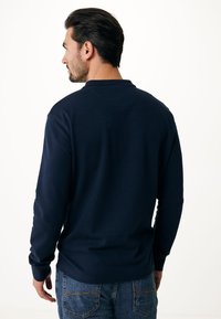 Marineblaues Langarmshirt mit Rundhalsausschnitt, gerippten Bündchen und glatter Textur, kombiniert mit blauen Denim-Jeans.