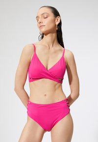 Różowy bikini składający się z bluzki w stylu owiniętym oraz spodni z wysokim stanem z bocznymi wycięciami. Gładka tekstura i regulowane ramiączka zapewniające idealne dopasowanie.
