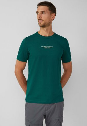 Grünes Baumwoll-T-Shirt mit kurzen Ärmeln und rundem Halsausschnitt, mit weißem Text "S.OLIVER UNBOUND SINCE 1969" auf der Brust.