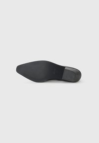 Semelle de chaussure noire, en caoutchouc, avec une surface lisse, une forme légèrement pointue et de subtils motifs texturés. Logo de la marque visible.