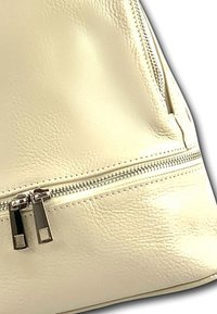 Crème leren handtas met een zachte textuur, uitgerust met een dubbele ritssluiting en accenten in zilverkleurig beslag.