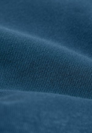 Blauer Baumwollstoff mit glatter Textur, der diagonale Linien und ein leicht geripptes Muster aufweist, gefaltet, um Tiefe und Glanz zu zeigen.