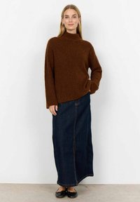 Brun ribbad polotröja, avslappnad passform. Lång denimkjol med en framseam och svarta platta skor. Enkel, neutral färgpalett.