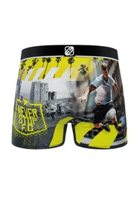 Un caleçon avec une ceinture noire, des accents jaune vif, des motifs graphiques de sport et le texte "NEVER STOP F.C." dans un design audacieux.