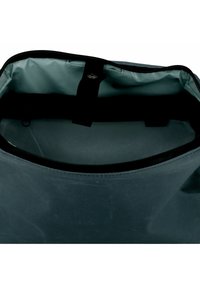 Interior de una bolsa resistente al agua de color gris que presenta una textura suave, cierre con cremallera y punto de sujeción para correa ajustable.