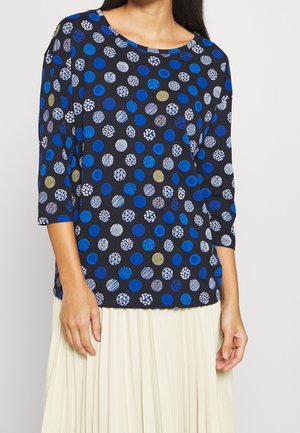 Zwarte top met driekwart mouwen, versierd met multikleurige stippen in blauw, wit en goud, gemaakt van een zachte, gestructureerde stof.