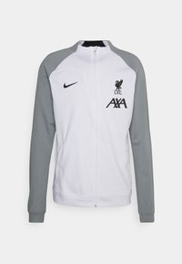 Chaqueta blanca con cremallera y mangas grises, con el logo del Liverpool FC y la marca AXA. Fabricada con un material ligero y suave.