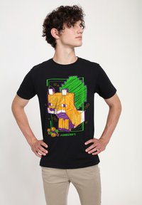 Camiseta negra con un gráfico de un zorro naranja pixelado, delineado en púrpura con acentos verdes, y la palabra "Minecraft" en la parte inferior.