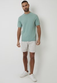 Lichtgroen shirt met korte mouwen van gebreid materiaal met een gestructureerd patroon, gecombineerd met lichte shorts en witte sneakers, met een ronde halslijn.