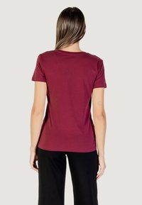 T-shirt corto color marrone scuro in morbido cotone. Presenta un collo rotondo e una vestibilità comoda. La vista dal retro mostra un tessuto uniforme e senza motivi.