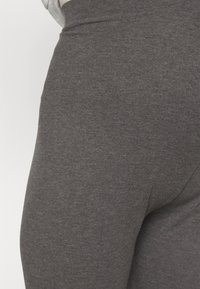 Szare legginsy o gładkiej fakturze, z wysokim stanem i dopasowanym krojem, podkreślające subtelny heather wzór w całej powierzchni.