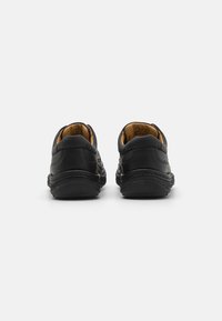 Black leather shoes with rounded backs, featuring stitching detail and a smooth finish. Interior lined with tan material for comfort.