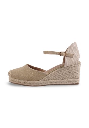 Sandale espadrille beige à talon compensé avec bout fermé, bride à la cheville et semelle en jute tressée sur fond blanc.