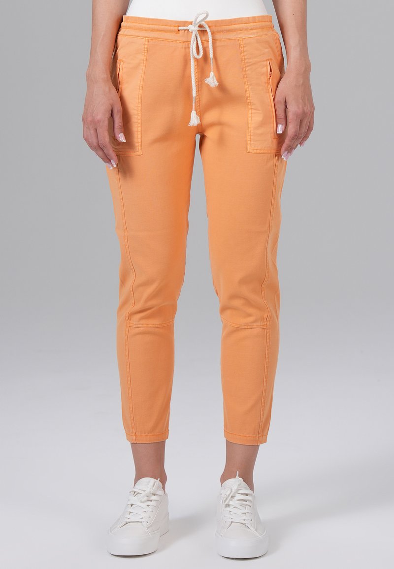 Felgekleurde oranje joggingbroek van zacht materiaal; heeft zijzakken, een elastische tailleband met trekkoord en een taps toelopend ontwerp.