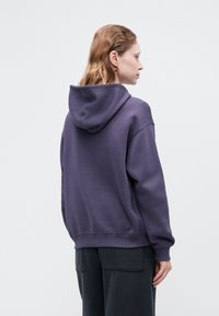Sudadera púrpura de corte relajado, con ribetes en el dobladillo y los puños, capucha con cordón y un suave material mezcla de algodón.