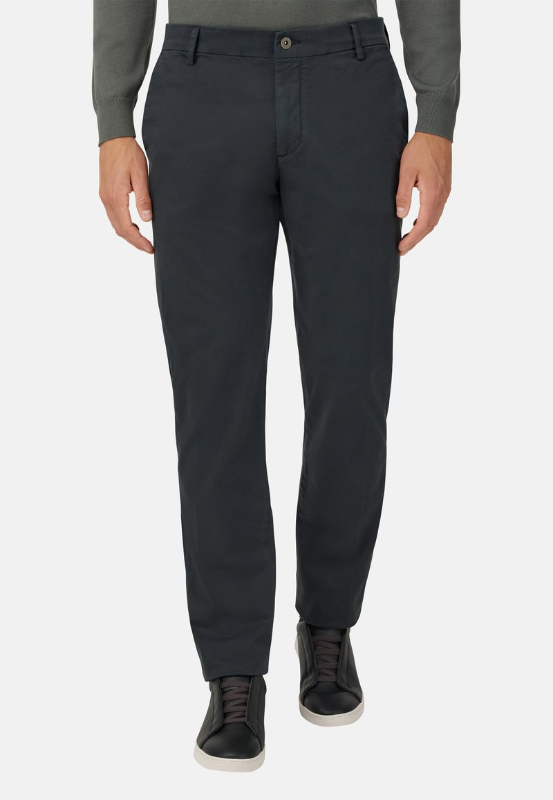 Tmavosivé, slim-fit nohavice vyrobené zo hladkej zmesi bavlny, s gombíkovým zapínaním a detailmi vrecka, v kombinácii s čiernymi teniskami.