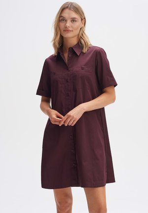Burgundy short-sleeve dress featuring a button-up front, two breast pockets, and a relaxed fit, made from smooth, lightweight fabric.