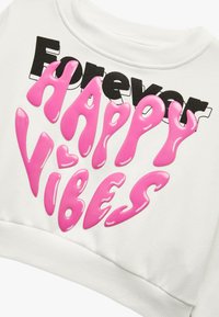 Biała krótka bluza z napisem "Forever" chamskim czarnym tekstem oraz "HAPPY VIBES" w błyszczącym różowym kolorze, o gładkiej fakturze.