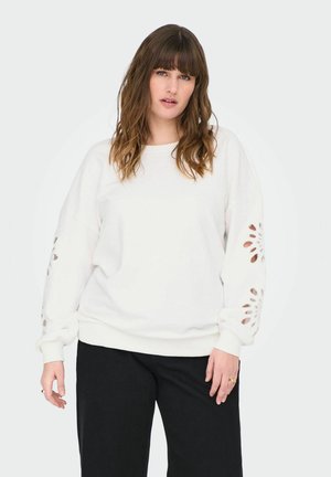 Felpa bianca con maniche lunghe, caratterizzata da ritagli floreali sulle maniche. Tessuto morbido, vestibilità rilassata e polsini a costine. Abbinata a pantaloni neri.