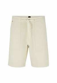 Béžové volné šortky s předními nášivkami, pasem na šňůrku se metalickými konci a nenápadnou značkovou štítkou na zadním pasu.