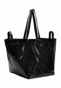Czarna torba na ramię wykonana z błyszczącego, teksturowanego materiału. Posiada dwa długie paski na ramię oraz przestronną, otwartą górę z ukośnymi narożnikami.