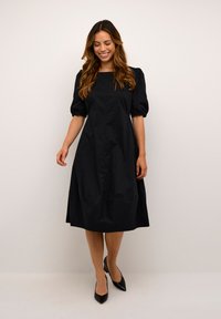 Robe noire à manches ballons avec un décolleté carré et une fermeture à boutons sur le devant. Fabriquée en tissu lisse, elle présente une silhouette évasée en A et arrive au niveau des genoux.