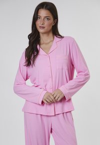 Rosa pyjamaset bestående av en knäppbar topp med bröstficka, långa ärmar och orange piping. Mjuk, texturerad tyg för komfort.