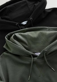 Dwie pofałdowane bluzy z kapturem, jedna czarna, a druga oliwkowo-zielona, z troczkami i widocznymi metkami marki "NEXT" wewnątrz kapturów.