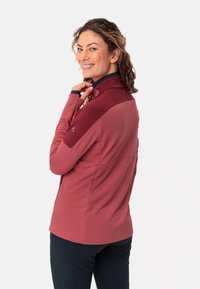 Giacca a maniche lunghe con zip di colore rosa tenue, con texture a costine e colletto blu; presenta un pannello a contrasto sulle spalle.