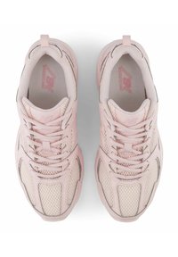 Light pink athletic shoes featuring a textured mesh upper, reinforced toe cap, and laces. Subtle gray accents enhance the design's depth.