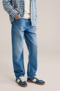 Ljusblå denimjeans med lös passform och en blekt tvätt. Matchade med marinblå sneakers, ljusa sulor och en rutig blå skjorta.