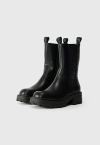 Crne kožne gležnjače s debelim potplatom, elastičnim bočnim panelima i petljama s ugraviranim natpisom "REPLAY".