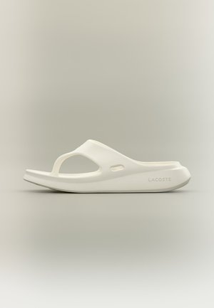 Sandale blanche Lacoste à enfiler avec une semelle large, un bout ouvert et une bride unique avec des trous de ventilation latéraux.