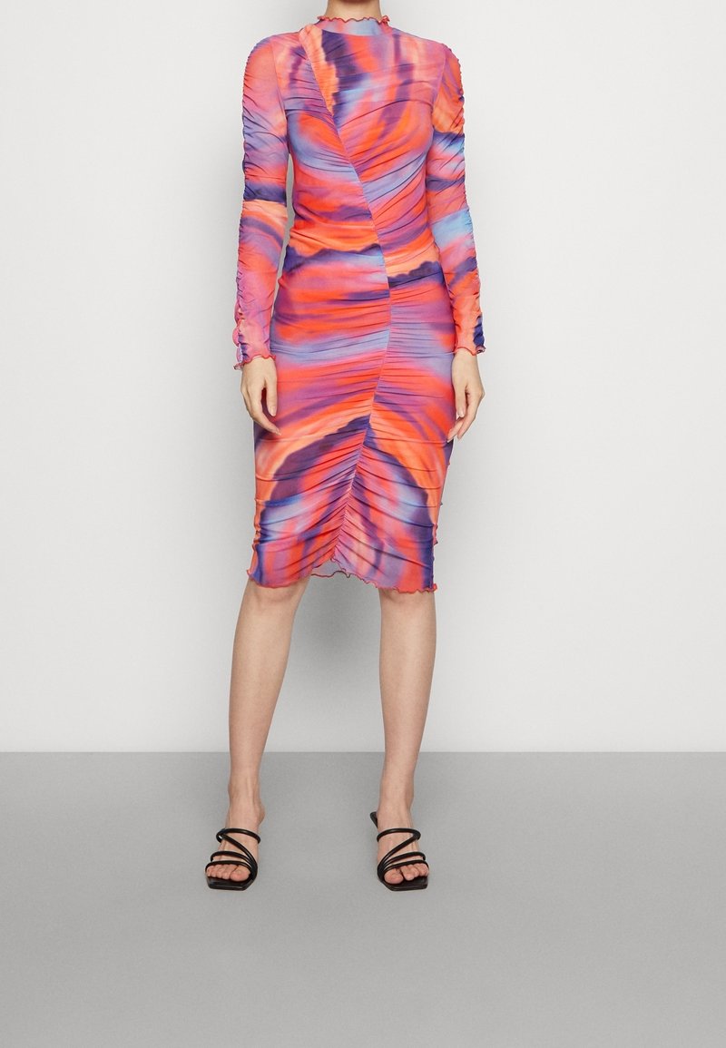 Figurnära klänning med långa ärmar, prydd med snurrande mönster i orange, rosa och blå nyanser. Volangkjol och rynkdetaljer genom hela plagget.