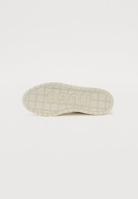 Semelle de sneaker de marque Hugo en caoutchouc blanc cassé, avec un motif de texture pour une meilleure adhérence et un logo en relief le long de la semelle intermédiaire.