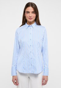 Camicia a maniche lunghe con strisce verticali azzurre e bianche, colletto button-down e chiusura con bottoni, con maniche a sbuffo.