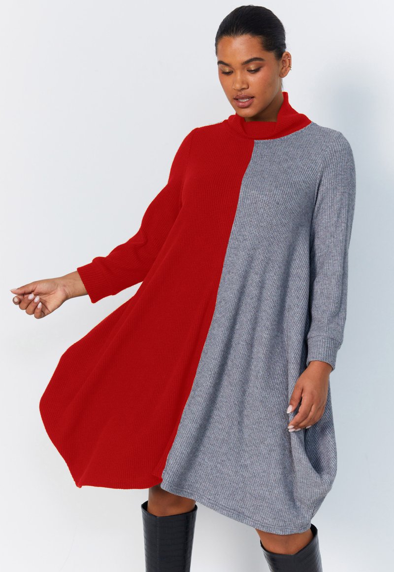 Robe en tricot avec un design de blocs de couleur rouge et gris, col montant, manches longues et une silhouette fluide. Accentuée par une texture côtelée.