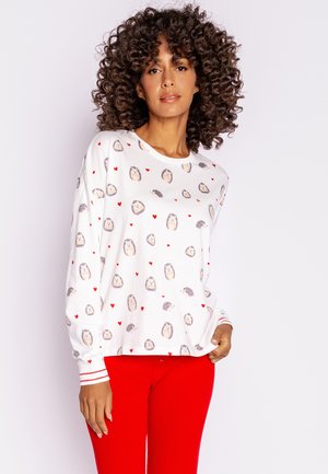 White long-sleeve top featuring a playful hedgehog and red heart print, with red striped cuffs. Paired with red ribbed pants.