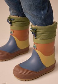 Färggranna gummistövlar med en färgpalett av brunt, blått, orange och grönt, med en texturerad brun sula och en grön mudd fodrad med fleece.